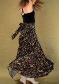 Load image into Gallery viewer, woman wearing a black and gold flowy skirt on a green gold backdrop.