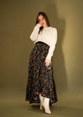 Load image into Gallery viewer, woman wearing a black and gold flowy skirt on a green gold backdrop.