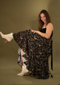 Load image into Gallery viewer, woman wearing a black and gold flowy skirt on a green gold backdrop.