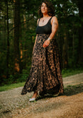 Load image into Gallery viewer, Woman wearing a black top and patterned skirt standing in a forest