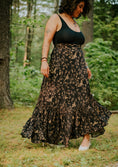 Load image into Gallery viewer, Woman wearing a black tank top and floral skirt standing in a forest