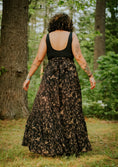 Load image into Gallery viewer, Person wearing a black tank top and patterned skirt walking in a forest.