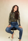 Load image into Gallery viewer, woman sitting on a chair in a studio wearing a mouse printed turtleneck and blue jeans.