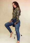 Load image into Gallery viewer, woman sitting on a chair in a studio wearing a mouse printed turtleneck and blue jeans.