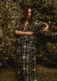 Load image into Gallery viewer, Woman wearing a patterned dress standing against a natural background